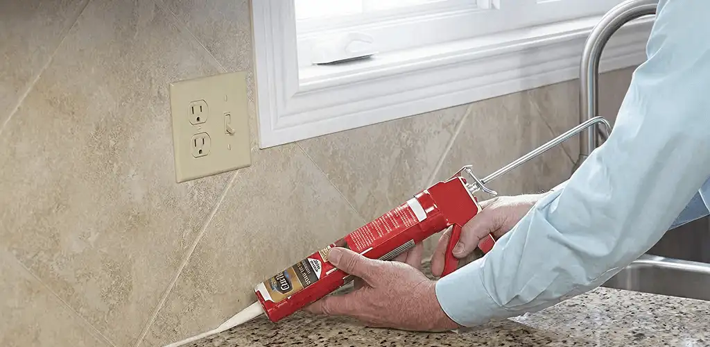 Handyman applying caulk along a kitchen backsplash and countertop seam in Richmond, VA