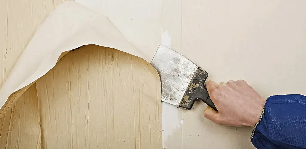 Handyman removing wallpaper with a scraper for wall preparation in Richmond, VA